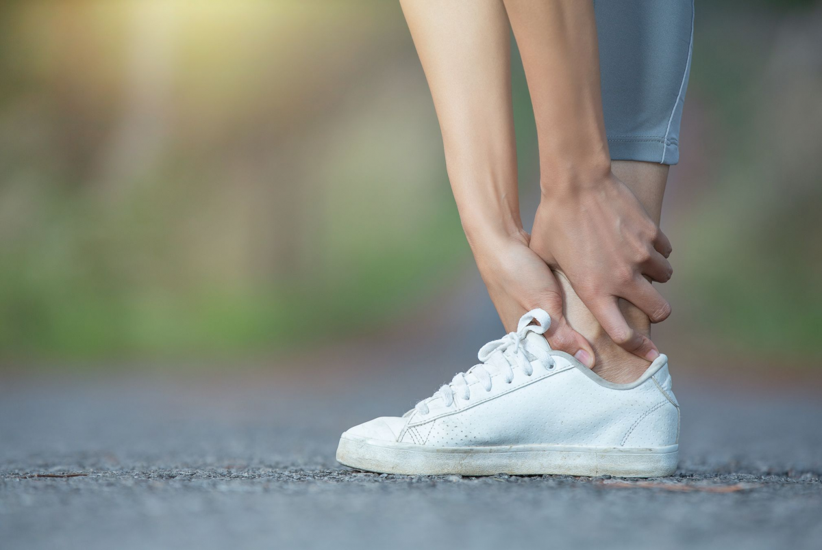 Seorang wanita memegang kakinya yang nyeri